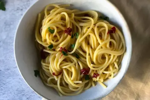 Spaghetti conditi con aglio, olio e peperoncino, guarniti con prezzemolo fresco. Un classico piatto italiano.