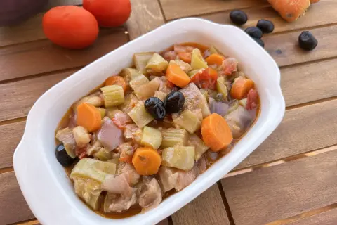 Un invitante piatto di caponata di verdure, con melanzane, carote, sedano e olive nere, pronto per essere gustato.
