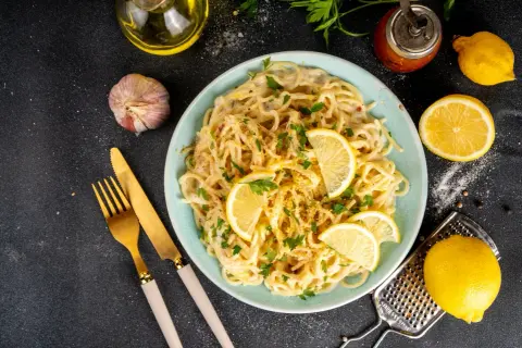 Spaghetti cremosi con un profumo agrumato, guarniti con spicchi di limone fresco e prezzemolo. Un piatto di pesto al limone che invita a gustare la freschezza.
