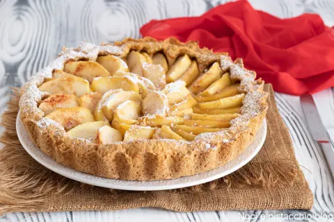 Una crostata di mele semplicissima, con mele a fette disposte a raggiera sulla base dorata, spolverata di zucchero a velo.