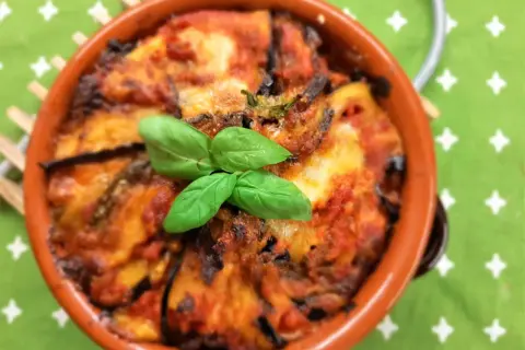 Deliziosa pasta alla norma al forno, con melanzane, pomodoro e basilico fresco, servita in una terrina di terracotta.