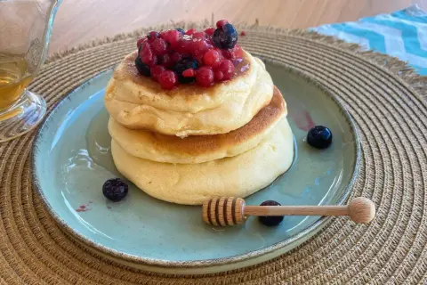 Pancake con albumi soffici, guarniti con frutti di bosco e miele. Un dolce leggero e goloso.