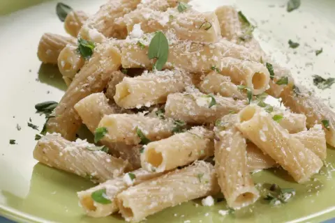 Maccheroni alla pastora conditi con formaggio grattugiato e erbe aromatiche fresche, un piatto semplice e gustoso.