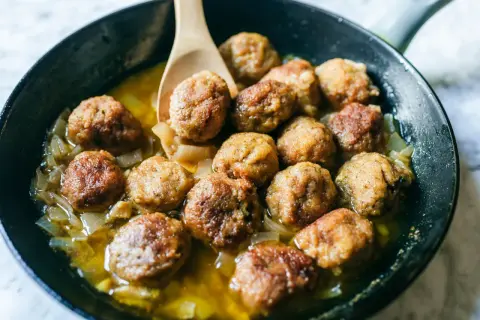 Polpette in bianco dorate e succulente, cotte in padella con cipolle dolci. Un classico confortante pronto per essere gustato.