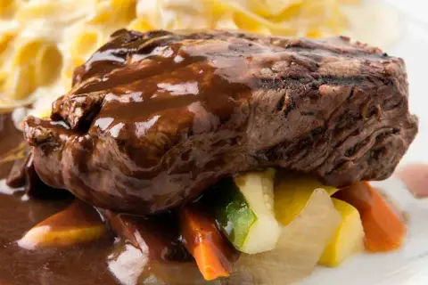 Succulento brasato al vino rosso su un letto di verdure miste e pasta all'uovo.