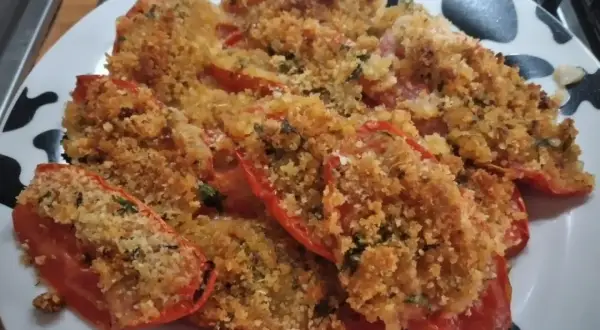 Pomodori gratinati al forno, un piatto saporito con pangrattato croccante e erbe aromatiche.