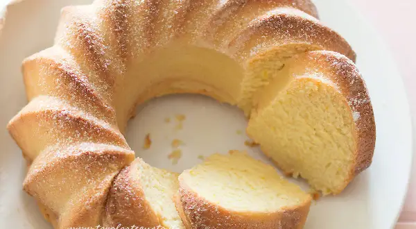 Deliziosa torta di ricotta, soffice e profumata, spolverata di zucchero a velo su un piatto bianco.