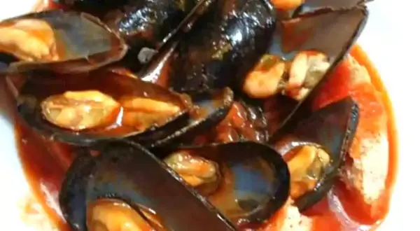 Un invitante piatto di zuppa di cozze al pomodoro, con cozze succulente immerse in un ricco sugo rosso.