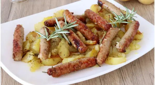 Salsicce e patate al forno, un piatto gustoso e profumato, con rosmarino fresco.
