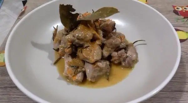 Delizioso spezzatino di tacchino in umido, con erbe aromatiche e una foglia di alloro, servito in una ciotola bianca.