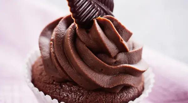 Un goloso cupcake al cioccolato con glassa cremosa e una decorazione a forma di foglia di cioccolato fondente.