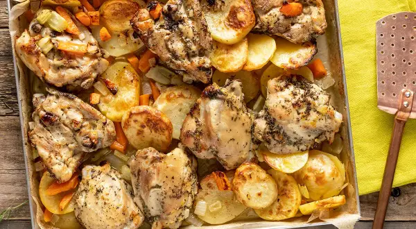 Sovracosce di pollo dorate al forno con patate, carote e sedano, un piatto succulento e profumato.