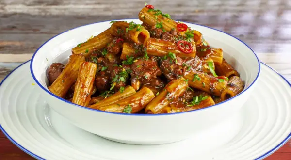 Rigatoni conditi con un saporito ragù di polpo, guarniti con prezzemolo fresco e peperoncino.