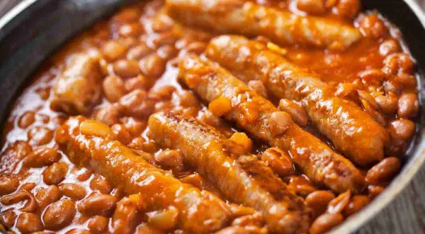 Salsiccia e fagioli in padella, un piatto confortante e saporito, con le salsicce dorate immerse in un letto di fagioli rossi in salsa.