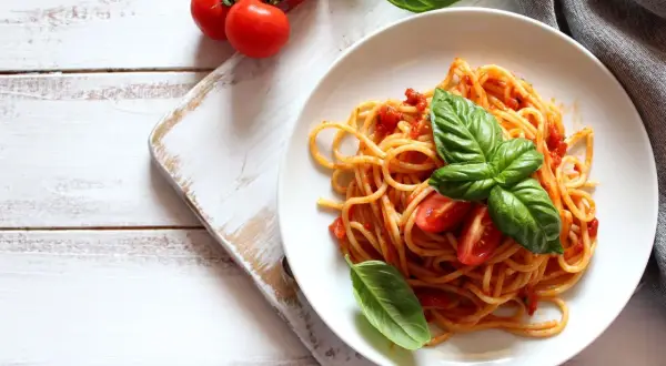 Spaghetti conditi con sugo di pomodoro fresco e basilico, guarniti con pomodorini. Un piatto semplice e gustoso.
