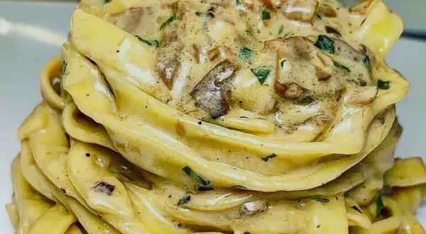 Un nido di tagliolini al tartufo cremosi, conditi con funghi e prezzemolo fresco.