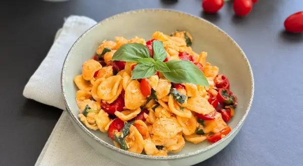 Orecchiette alla crudaiola con pomodorini freschi, basilico e un tocco di formaggio, un piatto estivo da gustare.