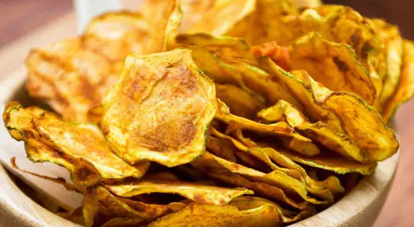 Croccanti zucchine al forno, dorate e saporite, servite in una ciotola di legno.