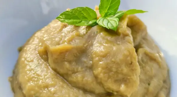 Un cremoso pesto di melanzane, guarnito con foglie di menta fresca, pronto per essere gustato.