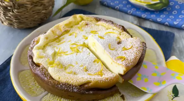 Una deliziosa torta ricotta veloce, spolverata di zucchero a velo e scorza di limone, servita su un piatto a forma di limone.