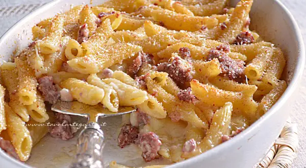 Un invitante piatto di pasta al forno con salsiccia, gratinata e dorata, pronta per essere gustata.