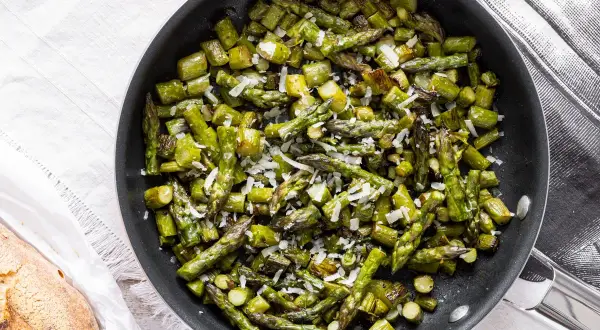 Asparagi verdi in padella, saltati e cosparsi di parmigiano grattugiato, pronti per essere gustati.