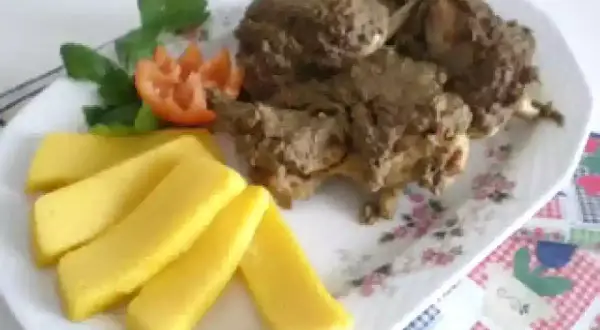 Piatto di coniglio in bianco con polenta e guarnizione di pomodoro e prezzemolo.