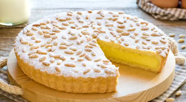 Una deliziosa torta della nonna, con crema gialla e pinoli tostati, spolverata di zucchero a velo.