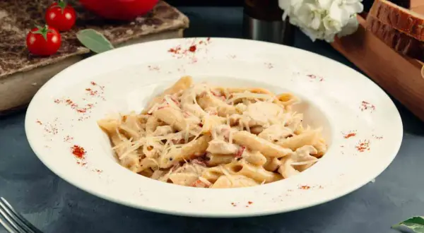 Piatto di pasta del pastore con crema, pollo e formaggio grattugiato, guarnito con paprika.