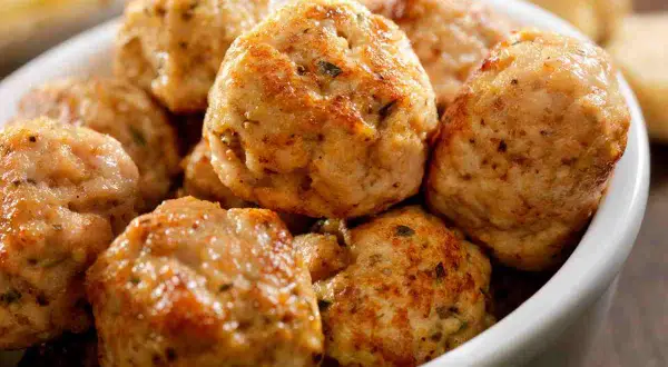 Un primo piano di polpette di tacchino dorate e saporite in una ciotola bianca, pronte per essere gustate.
