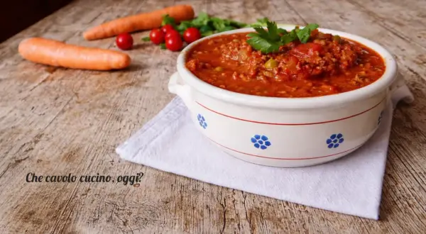 Un invitante sugo con macinato veloce, pronto per condire la pasta. Carote e pomodorini freschi completano la scena.