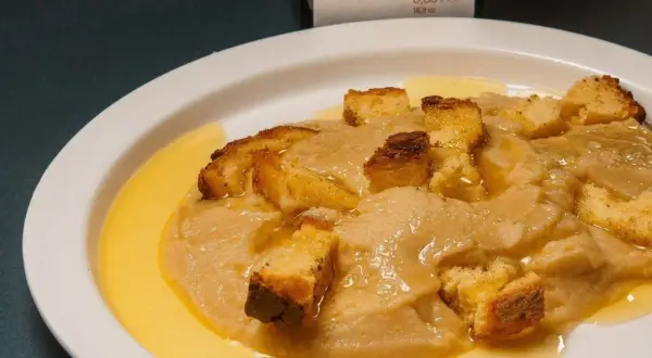 Piatto di crema di parmigiano con crostini dorati e un filo d'olio.