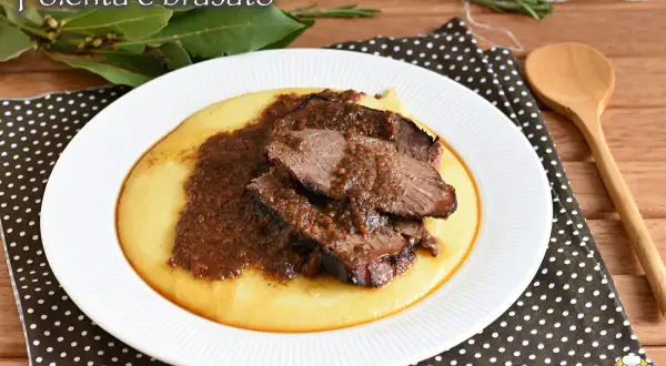 Piatto di polenta cremosa con fette di brasato di manzo succulento e salsa scura.