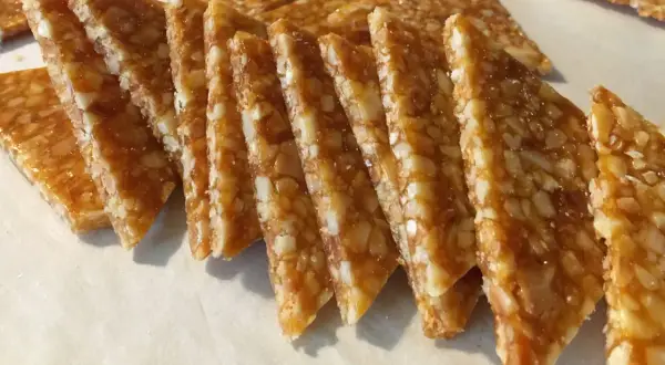 Fette triangolari di croccante di mandorle dorato, con mandorle tritate immerse in caramello lucido.