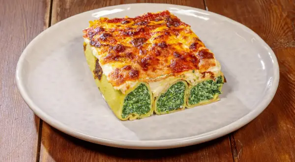 Crespelle alla fiorentina, rotoli di pasta ripieni di spinaci e ricotta, gratinati al forno con formaggio fuso.