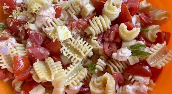 Pasta fredda con pomodoro, mozzarella, gamberetti e scorza di limone, un piatto estivo perfetto.