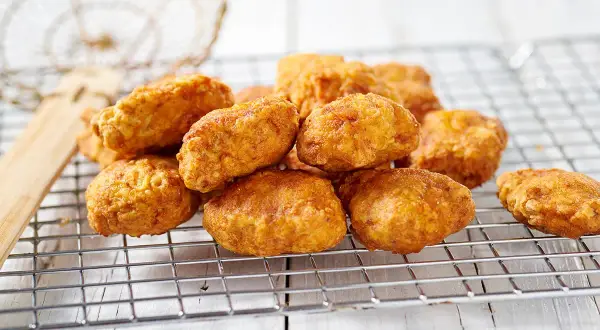 Nuggets fatti in casa dorati e croccanti, appena scolati su una griglia.