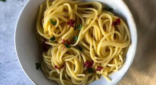 Spaghetti conditi con aglio, olio e peperoncino, guarniti con prezzemolo fresco. Un classico piatto italiano.