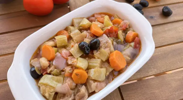 Un invitante piatto di caponata di verdure, con melanzane, carote, sedano e olive nere, pronto per essere gustato.