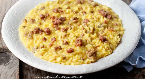 Un cremoso risotto con salsiccia, servito su un piatto bianco, pronto per essere gustato.