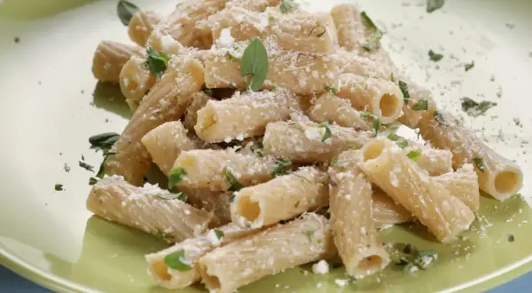 Maccheroni alla pastora conditi con formaggio grattugiato e erbe aromatiche fresche, un piatto semplice e gustoso.