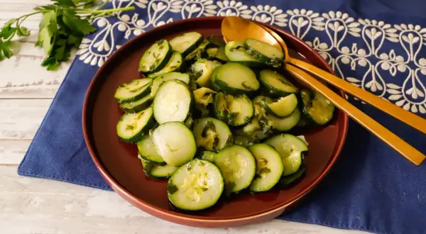 Zucchine trifolate bimby, un contorno semplice e gustoso, servite su un piatto marrone con cucchiai dorati.