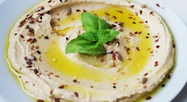 Hummus cremoso con semi misti e basilico, perfetto per idee pranzo veloci e gustose.