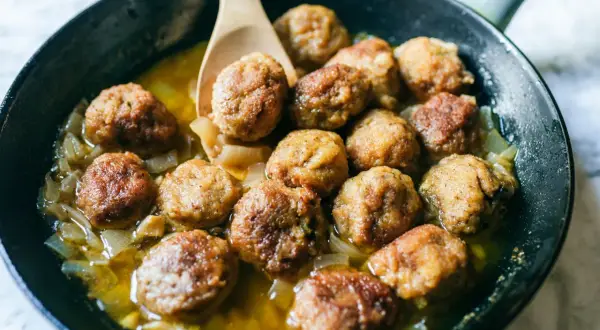 Polpette in bianco dorate e succulente, cotte in padella con cipolle dolci. Un classico confortante pronto per essere gustato.