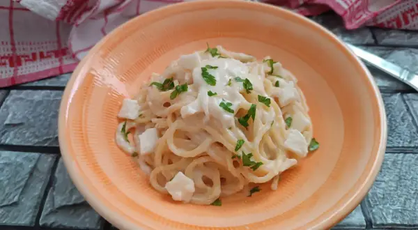 Spaghetti cremosi con cubetti di mozzarella di bufala e prezzemolo fresco, un piatto semplice e delizioso.