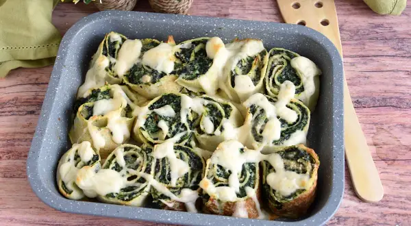 Girelle di crepes con spinaci e formaggio filante, un piatto invitante e gustoso.
