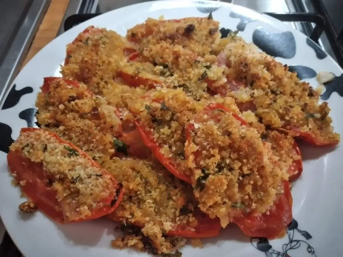 Pomodori gratinati al forno, un piatto saporito con pangrattato croccante e erbe aromatiche.