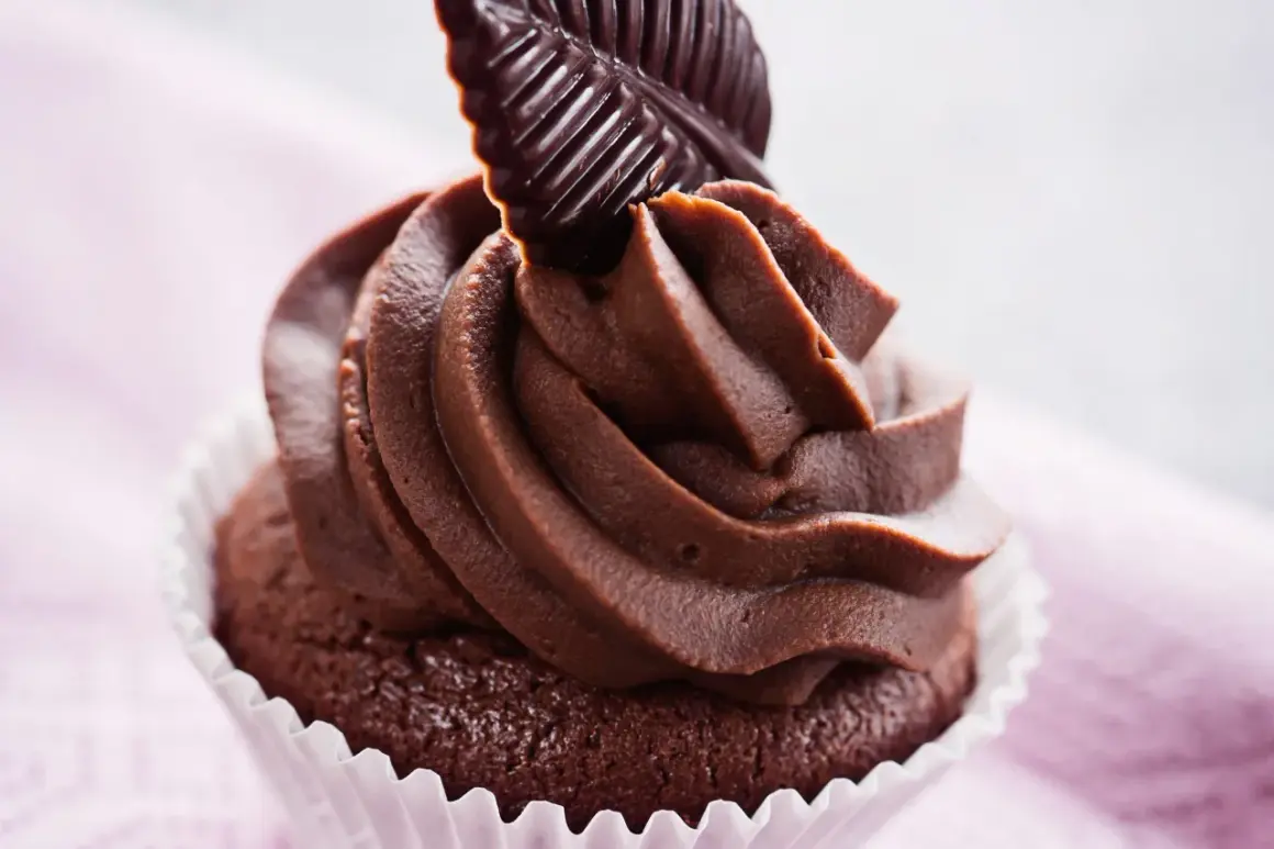 Un goloso cupcake al cioccolato con glassa cremosa e una decorazione a forma di foglia di cioccolato fondente.