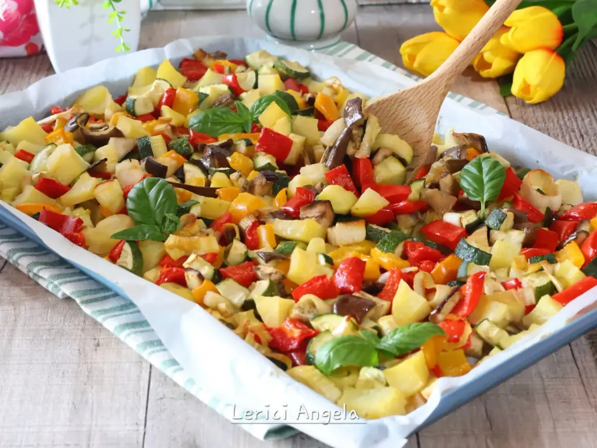 Un colorato mix di verdure in padella, con patate, peperoni, zucchine e melanzane, guarnito con basilico fresco.