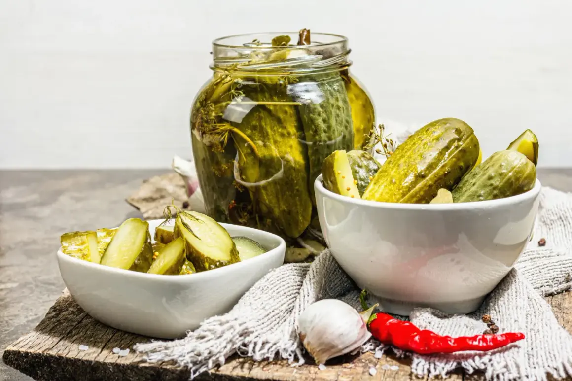 Cetrioli in agrodolce in un barattolo di vetro e in ciotole, con aglio e peperoncino.